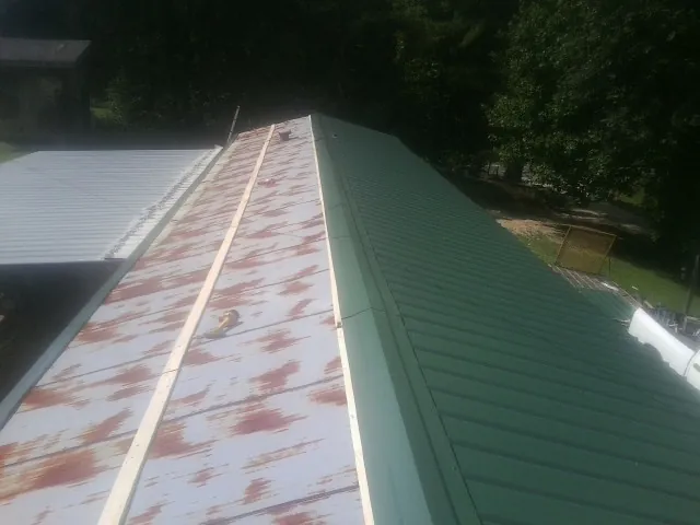Old rusted panels beside newly installed green metal roofing — Wind Damage Roof Repair by Roofing Brothers in Ahoskie