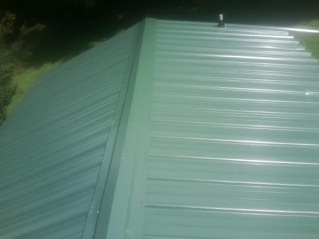 New green metal panels meeting at the ridge of a roof — Flat Roof Repair work by our crew in Ahoskie