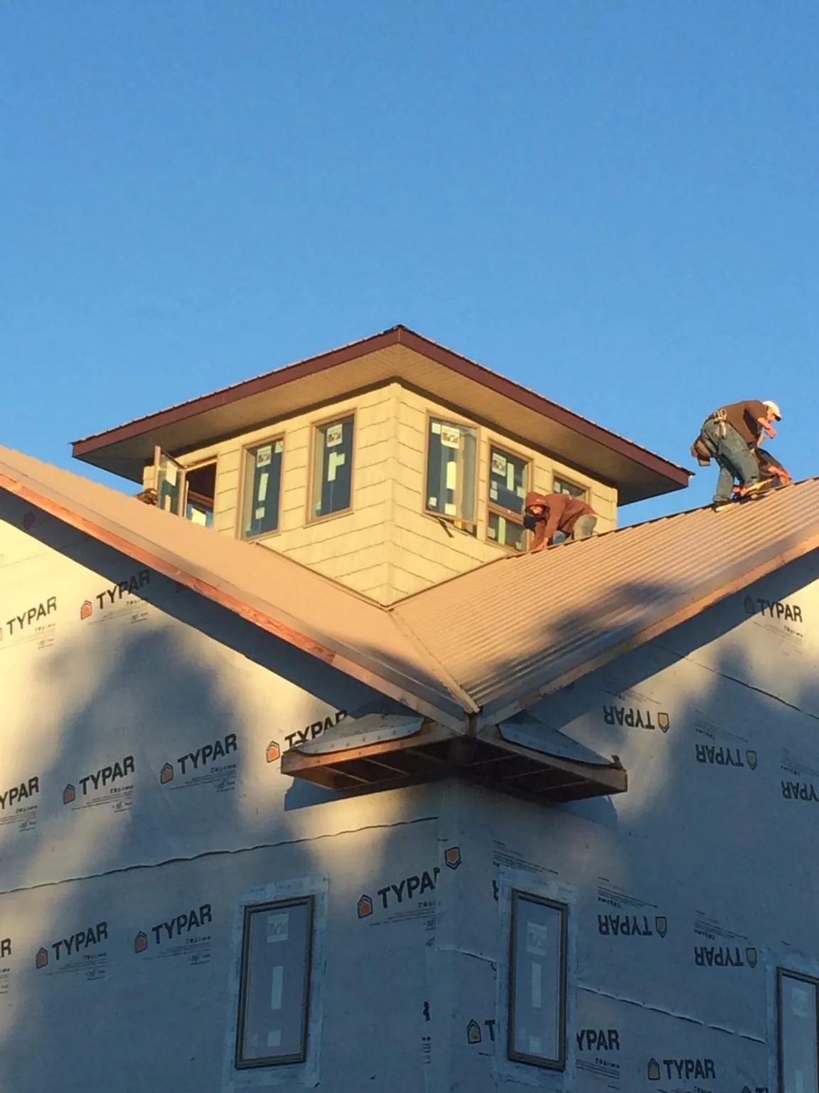 Roofers working around a rooftop cupola on a new metal roof at sunset — Roof Waterproofing in Ahoskie by Roofing Brothers